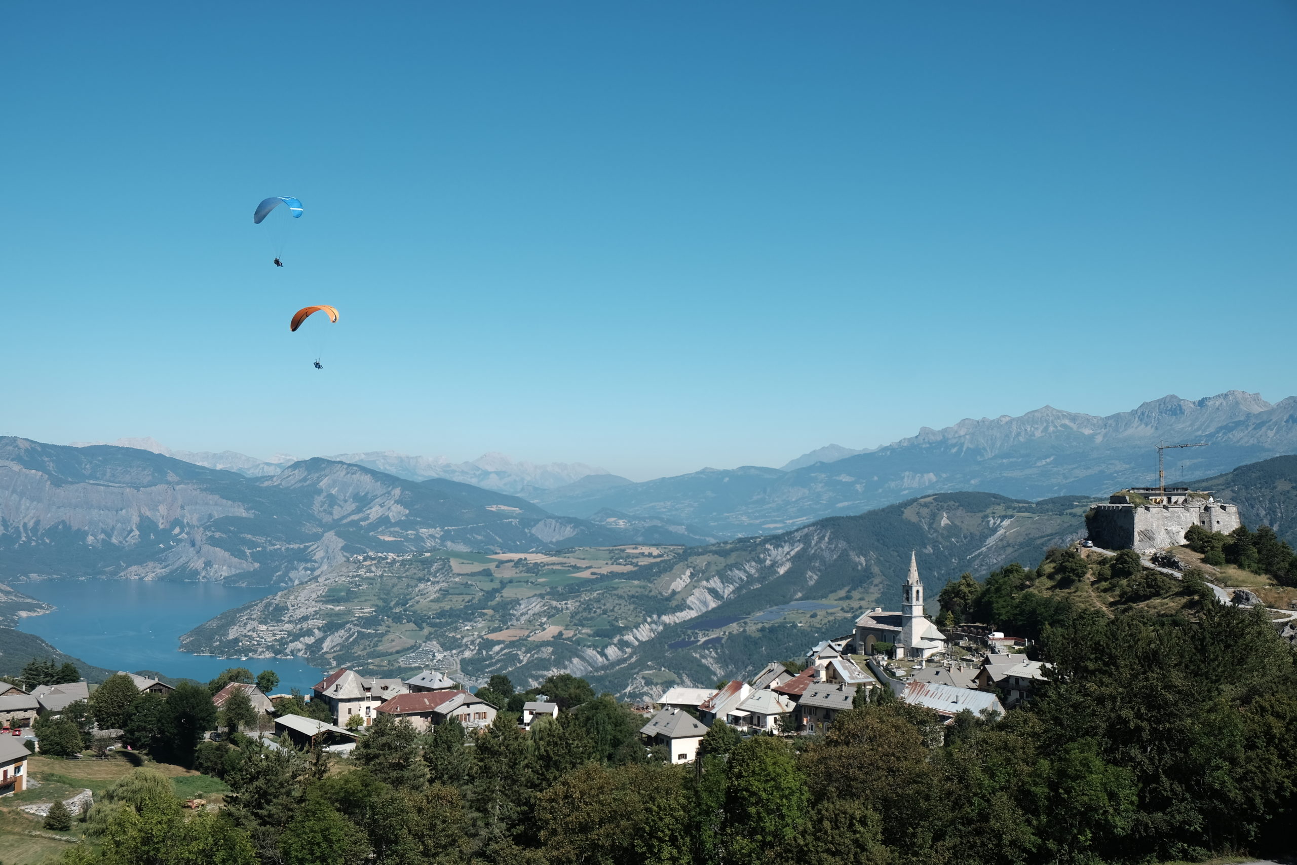 vue de loin, survol de Saint Vincent les forts par deux parapente