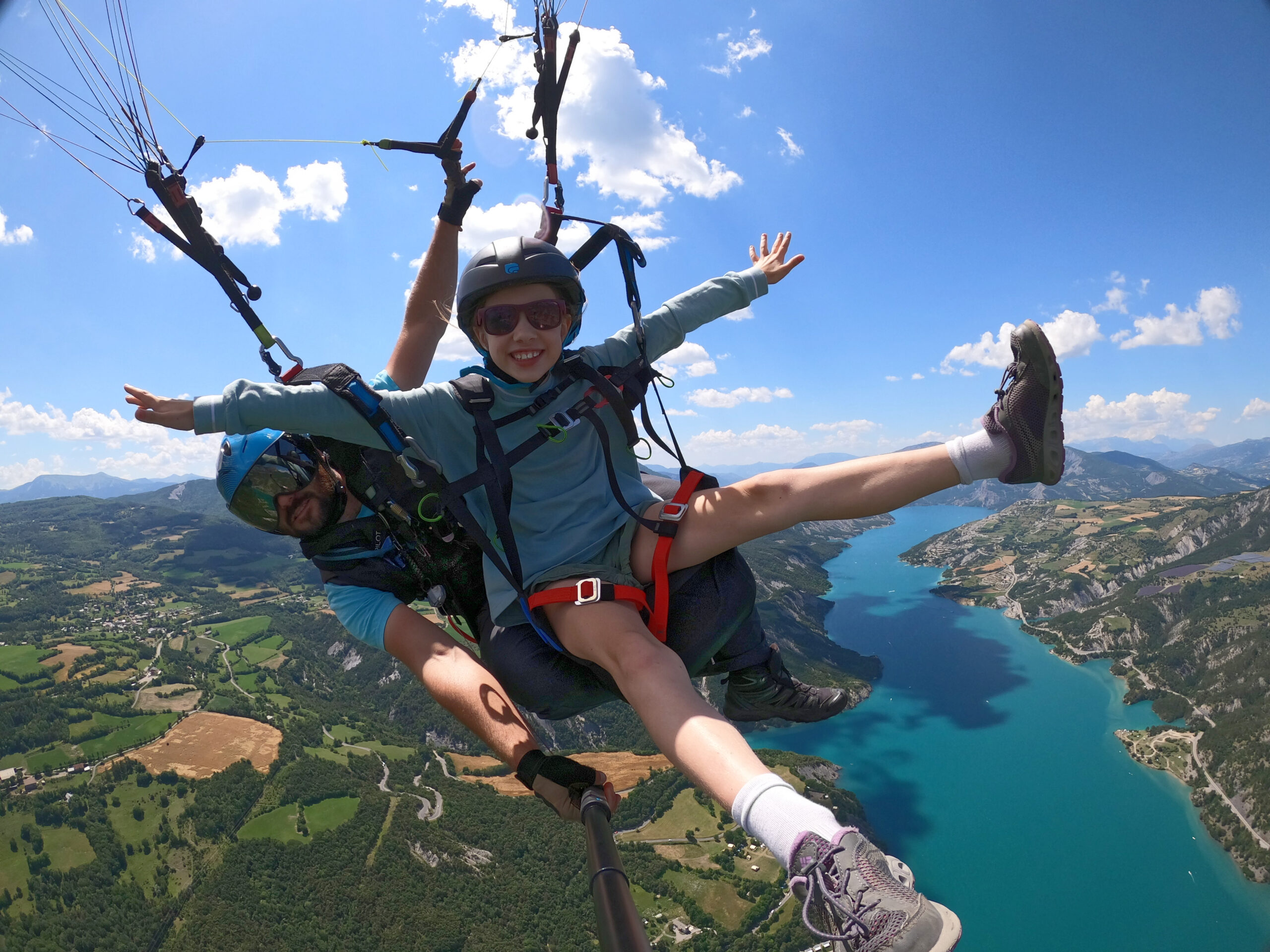 ça plane en parapente vol tandem avec une jeune passagère tout sourire.